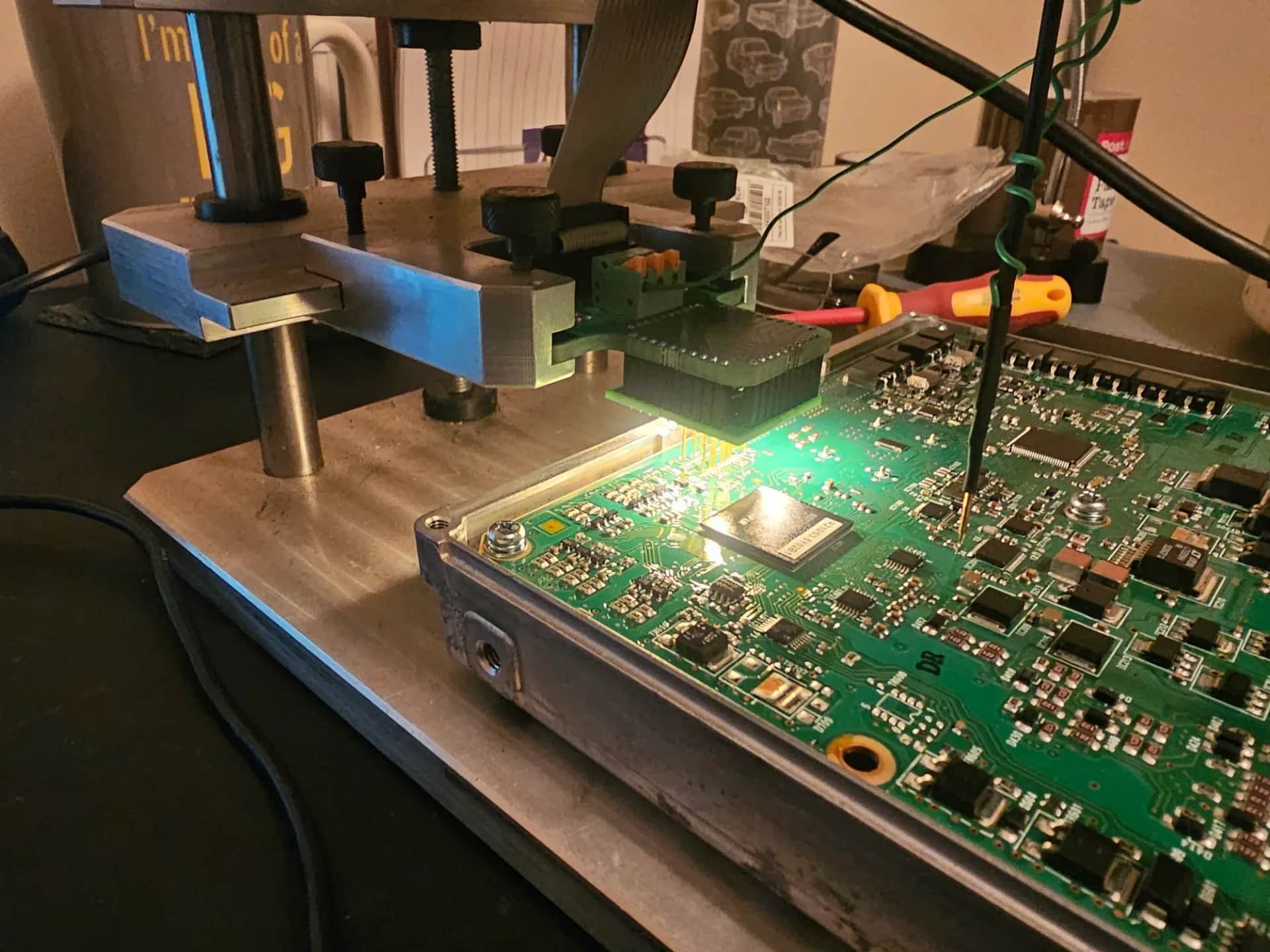 ECU opened on the bench — probes on the circuit board during a bench flash